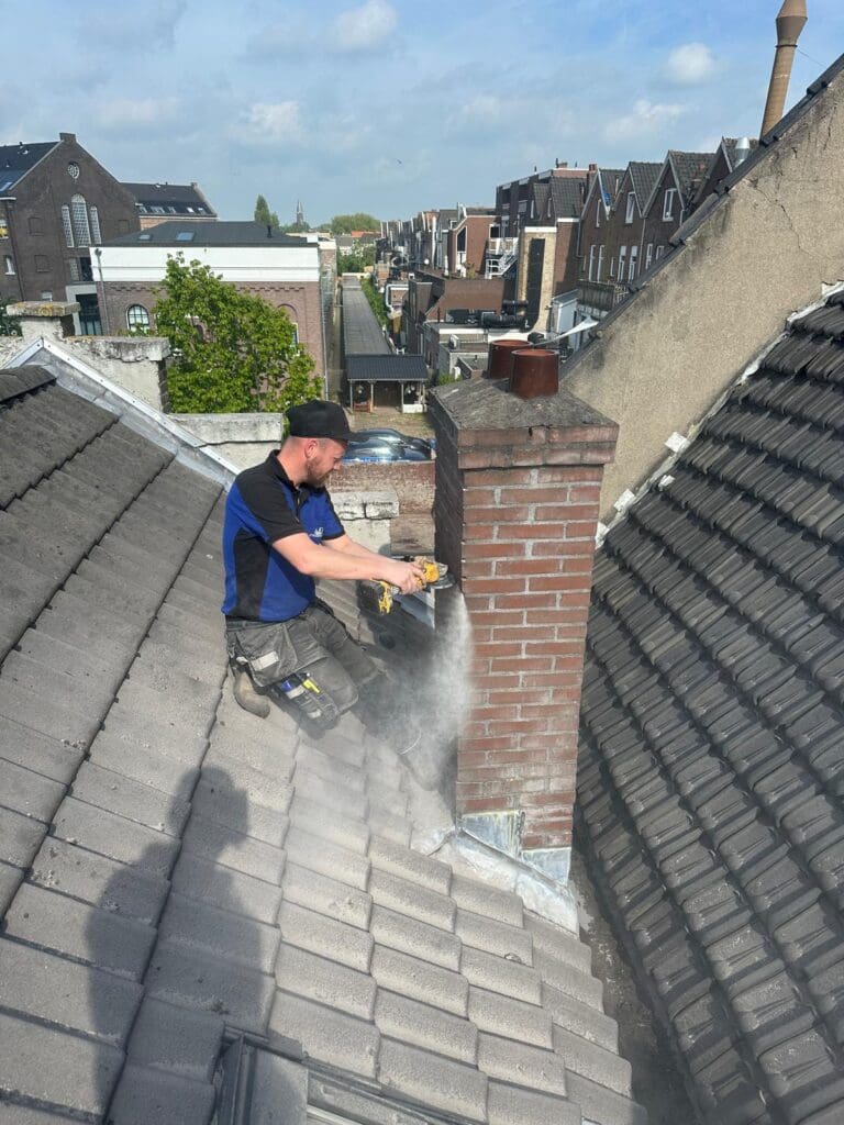 Dakdekker verwijdert oude dakpannen bij schoorsteen
